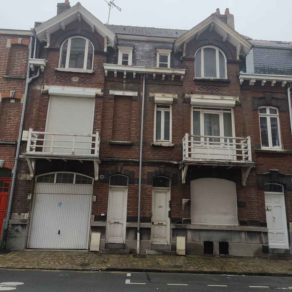 Deux maisons de rangées en briques jumelles à quelques détails près. Comme une fenêtre murée chez l'une et pas chez l'autre, ou encore une fenêtre devenue garage pour la voisine.