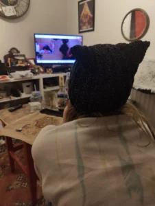 Photo d'une fille de dos portant un bonnet à oreilles de chat en regardant la télé.