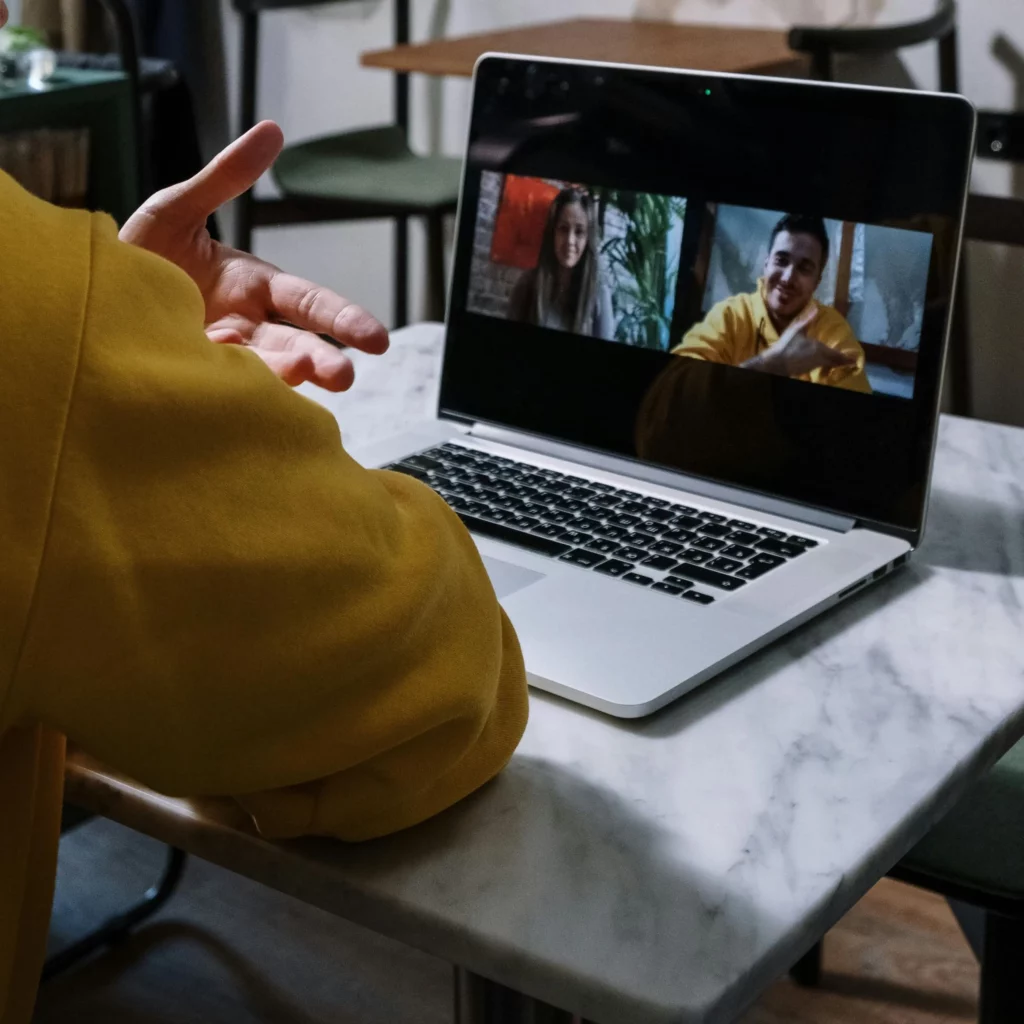 On devine le bras et la main d'une personne face à son ordinateur en visioconférence.