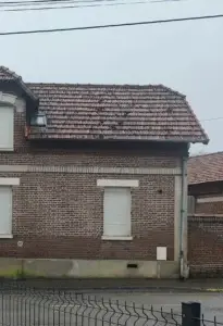 Frange d'évaporation visible sur façade en brique au-dessus du soubassement béton