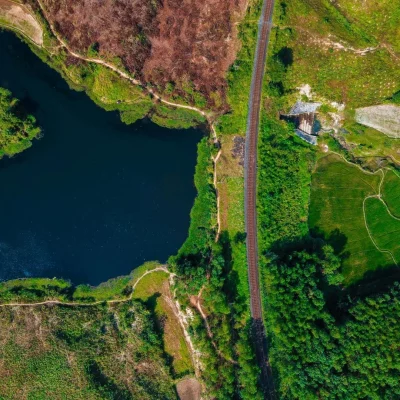 Vue du ciel sur une route avec un lac , des chemins, un bois, des sols en friche et d'autres cultivés, des carrières de pierre paraissent en gris.